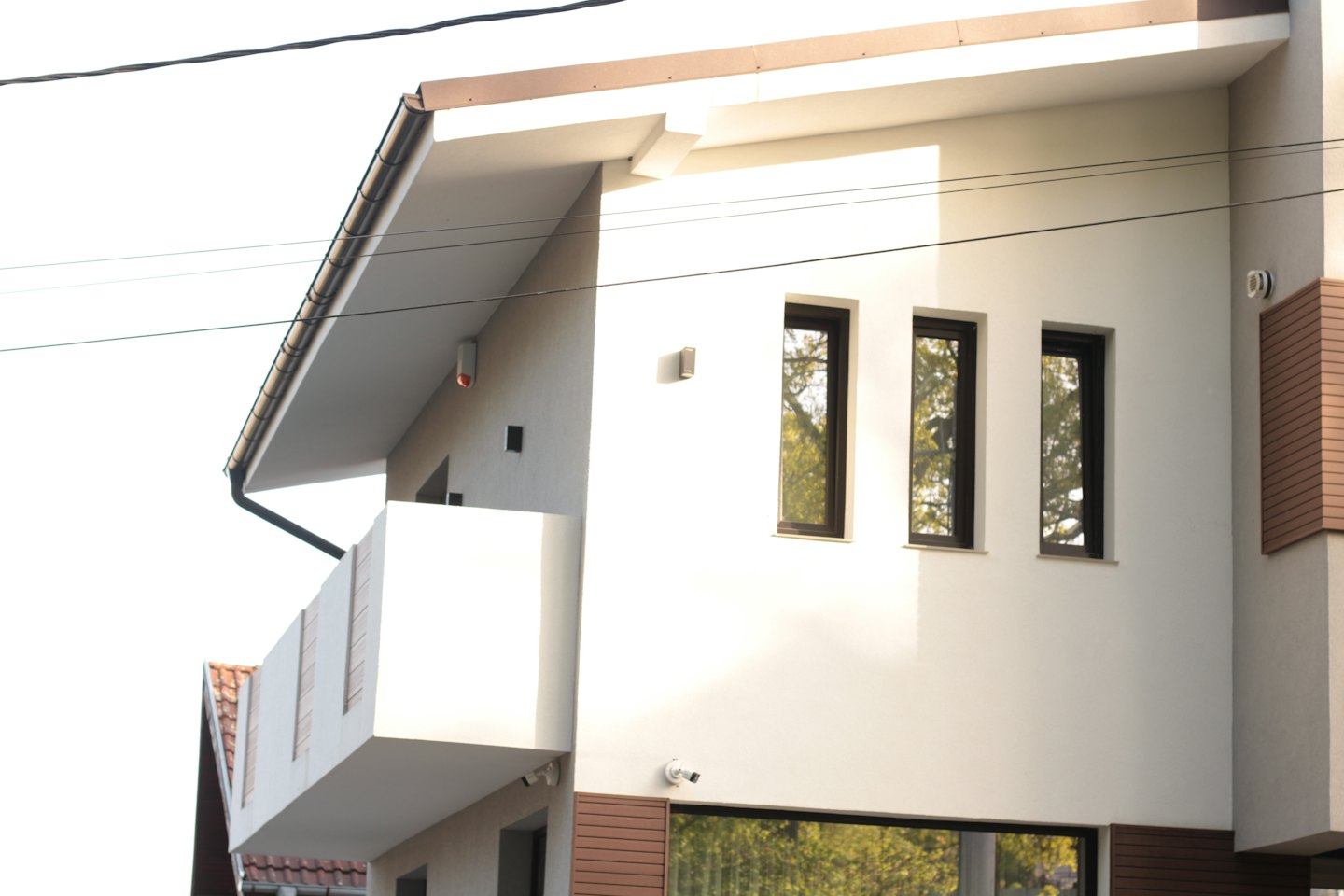 Modernes mehrstöckiges Haus mit weißer Fassade und dunklen Fenstern.